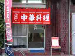 福岡市中央区のラーメン屋さん、「高倉軒」。店構え、赤い暖簾に白字で中華料理と書いてあります。入り口の横にいすが置いてあり、その上に今日の定食メニューを書いたホワイトボードがあります。
